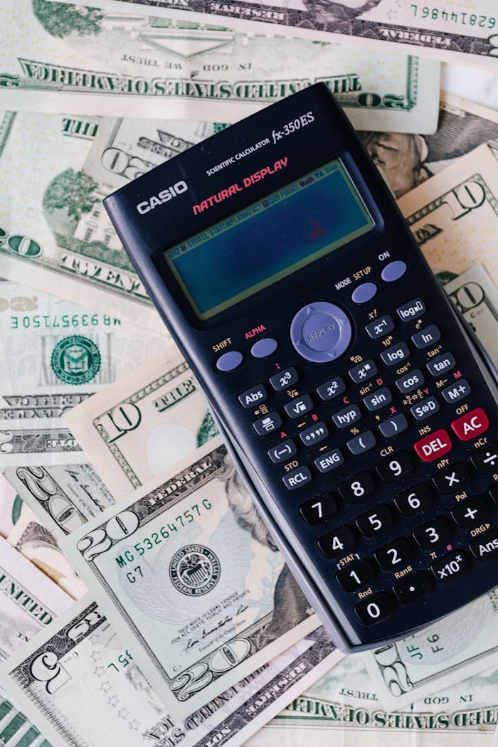 Services Scientific calculator placed on various US dollar bills, symbolizing finance and calculation concepts.