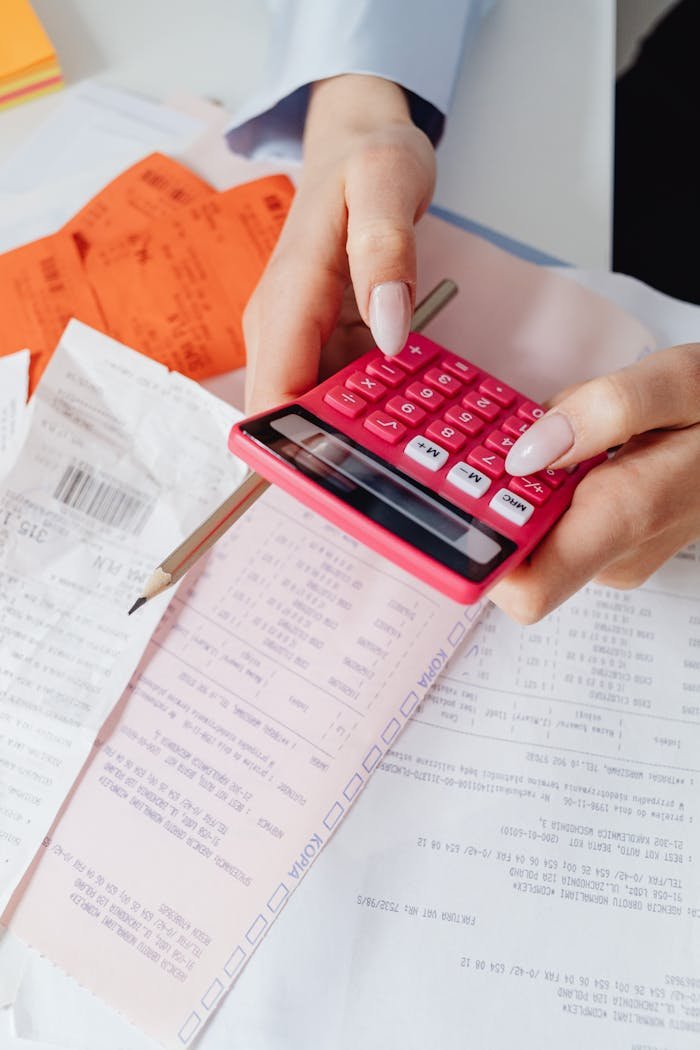 Services Hands using a red calculator surrounded by financial documents and receipts, symbolizing financial management.